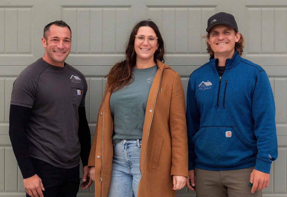 The Tis The Season holiday lighting team standing together in front of a garage door