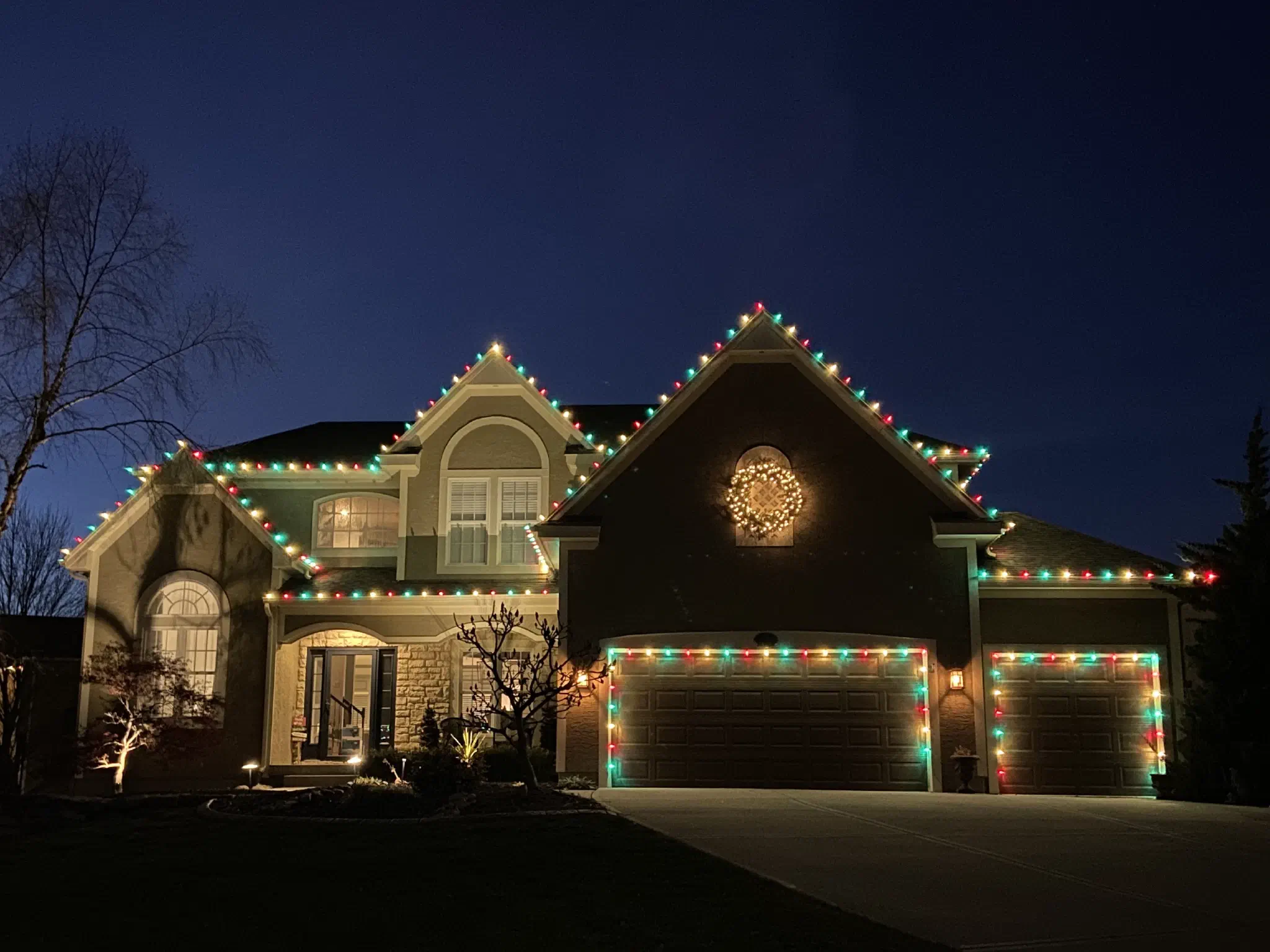 Full-home holiday lighting display with roofline and bushes