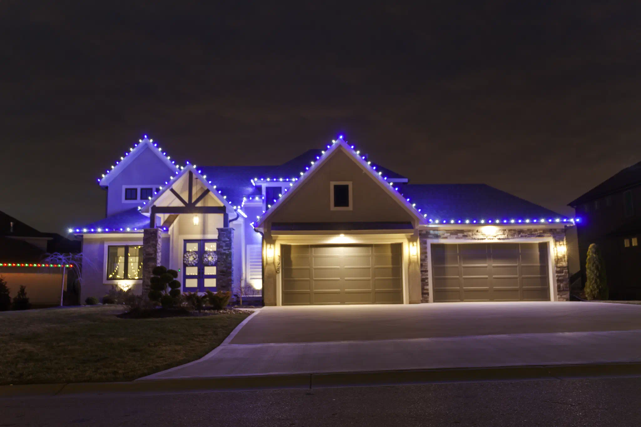 Full-home holiday lighting display with roofline and bushes