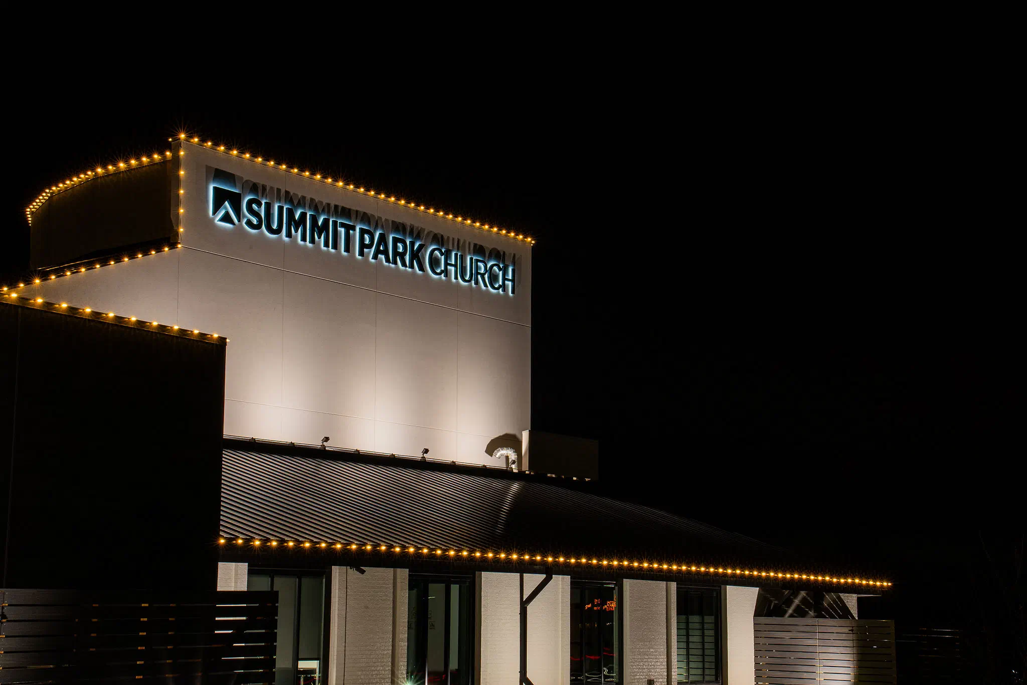 Summit Park Church building outlined in warm white commercial holiday lights at night